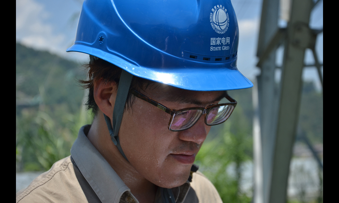 7月24日，福建福州供電公司輸電運檢室的工作人員頭頂烈日對220千伏東高線進行巡視。 （陳蒸 攝）