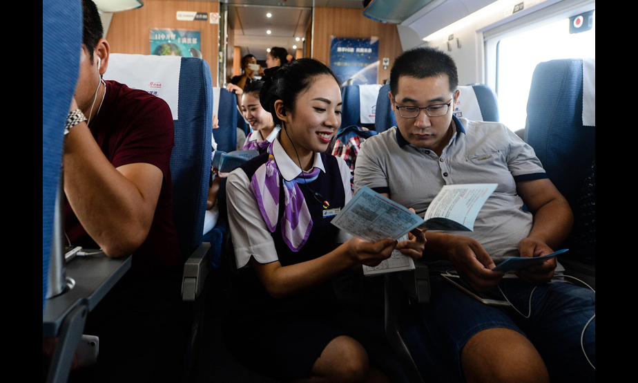 2016年9月10日，在上海虹橋站開往鄭州東站的G1802次列車上，乘務員夏夢雅給乘客發放宣傳資料，講解注意事項（季春鵬 攝）。