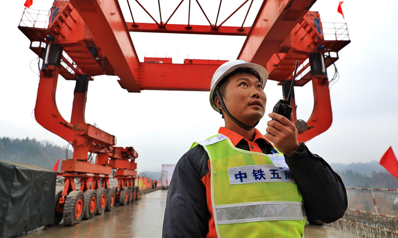 12月12日，在安六鐵路岱港村特大橋，中鐵五局工作人員指揮安裝箱梁。（新華社記者 劉續(xù) 攝）
