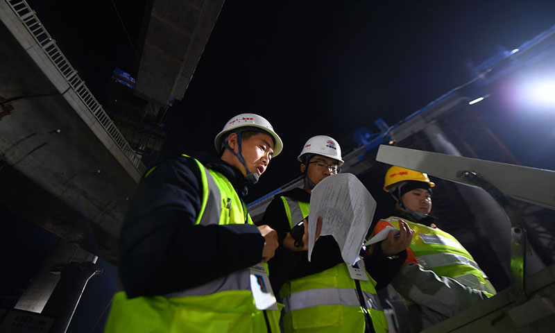 常益長鐵路全長157公里，設(shè)計時速350公里，是國家“八縱八橫”高速鐵路網(wǎng)的重要組成部分。圖為12月25日凌晨，中鐵十一局技術(shù)人員對照操作臺記錄轉(zhuǎn)體梁轉(zhuǎn)動角度和弧長。（新華社記者 趙眾志 攝）