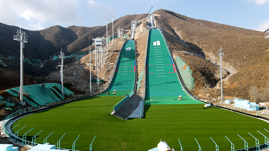 建設基地的賽道在設計中結合當地獨特的山體條件，讓崇禮滑雪跳臺“雪如意”的兩條賽道按照1:1的比例在此重現，被大家親切地稱為“雪吉祥”。“雪吉祥”滑雪跳臺著陸坡采用土方填筑施工，建設者在世界首次將高鐵施工中的高填方填筑技術應用于高山跳臺滑雪工程，有效加固了土體，保證了土方填筑的穩定性，滿足了設計沉降要求。圖為大跳臺和標準跳臺兩條賽道。