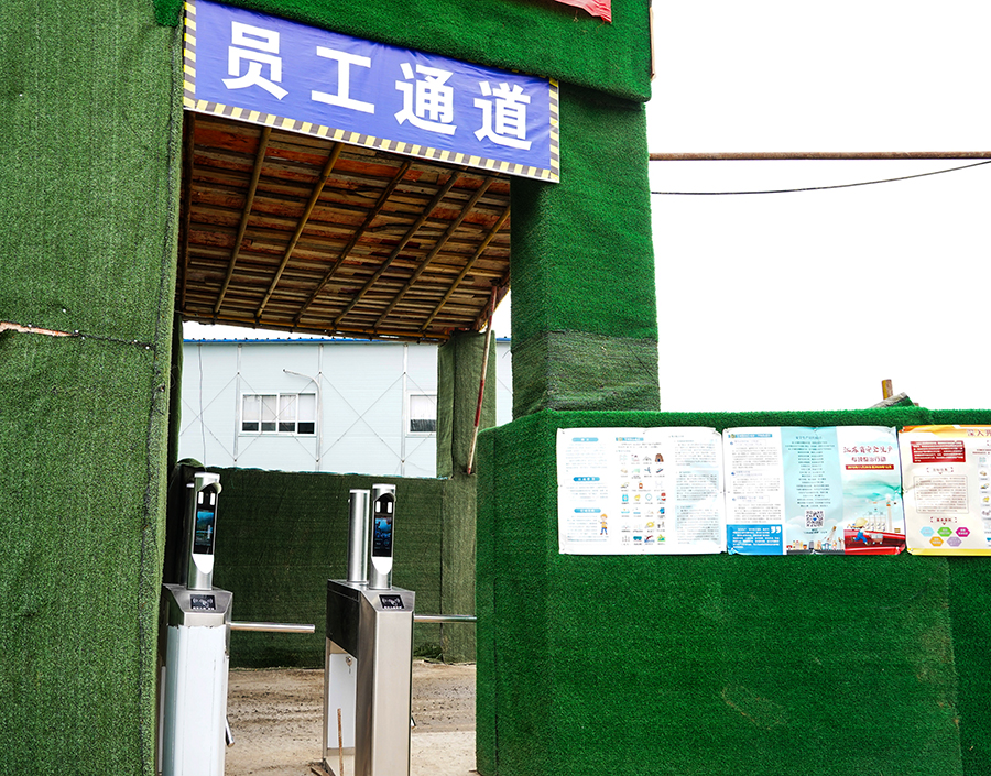 “攔住”張師傅的是中國(guó)鐵建所屬中鐵二十五局二公司南京仙林智谷項(xiàng)目部防疫檢測(cè)口新配備的刷臉設(shè)備。“當(dāng)大家戴著口罩進(jìn)入工區(qū)、項(xiàng)目部入口時(shí)，無(wú)須摘下口罩，和往常一樣刷臉就能通過門禁。”據(jù)介紹，這個(gè)設(shè)備可對(duì)佩戴口罩后的人臉進(jìn)行準(zhǔn)確識(shí)別，驗(yàn)證成功后,自動(dòng)發(fā)出信號(hào)打開門禁或閘機(jī)，記錄考勤信息；對(duì)未佩戴口罩或口罩佩戴不規(guī)范人員，拒絕通過，并報(bào)警提示值班人員。圖為值守在員工通道上的人臉識(shí)別系統(tǒng)。（王云海 攝） 