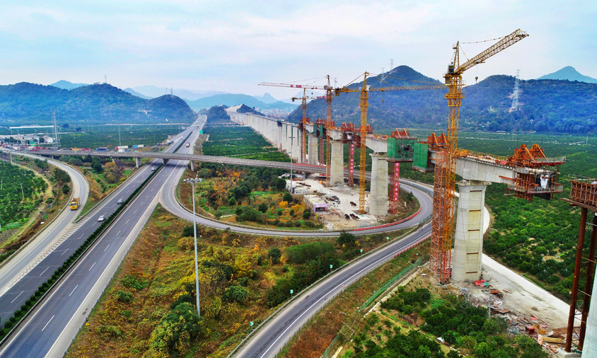 靈江特大橋上跨靈江航道、馬上線公路、S327省道、臺金高速公路，施工環境異常復雜，是全線關鍵性重難點控制工程。該橋在施工中不但要保證靈江及相鄰公路的正常通航通行、還面臨著深水基礎施工、大跨度連續梁施工線形監控等一系列施工難題。特別是位于靈江中的61-67號墩，鉆孔深度達95.945米。當鉆孔深度超過80米后，尤其在軟硬交互地層，控制樁孔的豎直度就成為一項重要的技術難題。由于樁孔直徑大、深，且存在較厚卵石層，非常容易造成護壁泥漿失效、孔壁局部或整體坍塌。因此，靈江特大橋施工也被稱為“在刀刃上跳舞”。圖為靈江特大橋連續梁合龍施工。
