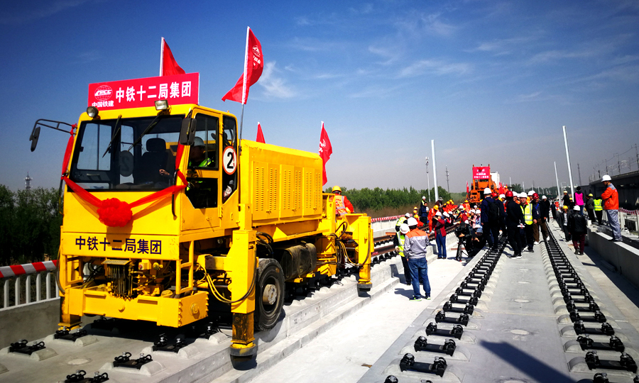 4月15日上午9時28分，在北京至雄安新區城際鐵路李營段施工現場，中國鐵建所屬中鐵十二局集團現場指揮人員一聲令下，第一組500米長鋼軌從T11運輸車前端緩緩送出，標志著京雄城際鐵路建設整體從線下施工轉入線上軌道鋪設階段，也意味著京雄城際鐵路（北京段）開通運營進入最后沖刺階段。圖為牽引長軌。