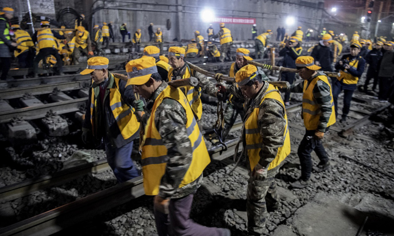 圖為1月15日凌晨，中鐵十一局施工人員在西安站改擴建工程現場抬運鋼軌。（新華社記者 陶明 攝）