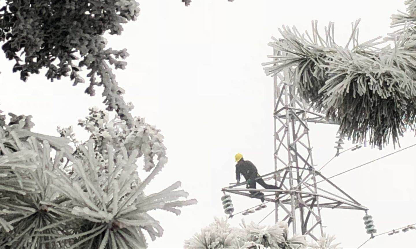 除冰人員登上覆滿冰雪的鐵塔上敲冰。 （趙英 攝）