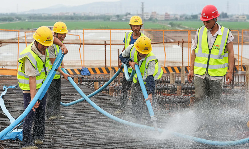 圖為5月1日，工人在珠海鶴港高速公路二期工程高欄港樞紐立交橋建設現場沖洗箱梁底板。（新華社記者 劉大偉 攝）
