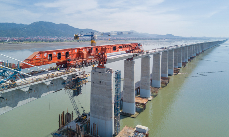 圖為7月11日，在新建福廈鐵路湄洲灣跨海大橋建設現場，中鐵十一局工人協同“昆侖號”千噸級運架一體機架設該線路最后一孔40米箱梁。（新華社記者 宋為偉 攝）