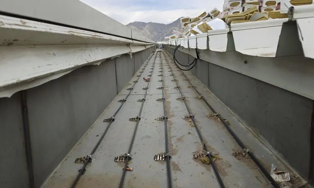 青藏高原冬季氣溫低，常規光照條件下積雪消融緩慢。天溝，即建筑物屋面兩跨間的下凹部分，陽光無法照射到，融化的雪水極易二次凍結，堵塞排水通道，產生滲漏風險，增加屋面荷載。為此，項目在天溝內鋪設了電伴熱線纜，給天溝裝上了“暖寶寶”。