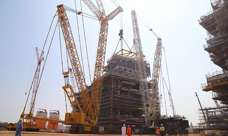 在中國海油海油工程建造事業(yè)部青島場地加拿大LNG項(xiàng)目模塊總裝區(qū)，經(jīng)過施工人員多天連續(xù)奮戰(zhàn)，加拿大LNG項(xiàng)目第二個(gè)Mini E-House（電氣間）精準(zhǔn)就位于A1EB模塊指定位置。圖為Mini E-House（電氣間）吊裝現(xiàn)場。