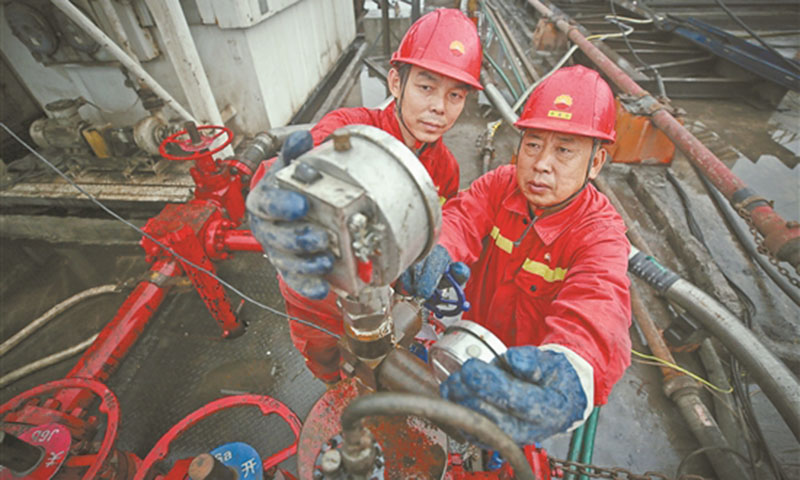 距離大慶油田3000多公里的川渝油氣增儲上產主戰場——大慶油田2萬多平方公里的流轉區塊所在地，一年四季云霧繚繞、山路崎嶇、靠山臨崖，井架藏身于大山深處，小井場中進行著大規模壓裂作業。圖為鉆井隊副司鉆牽頭檢查封隔器壓力表。