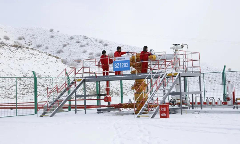 圖為中國石油塔里木油田博孜1202井采氣工對采氣樹積雪進行清理，防止雪水融化浸入電機引發故障。