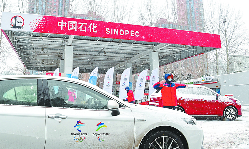 近日，北京冬奧會3個(gè)賽區(qū)迎來降雪。中國石化員工奮戰(zhàn)在一線，保障北京冬奧會期間油氣氫電平穩(wěn)供應(yīng)，成為漫漫大雪中的一道風(fēng)景線。圖為北京石油冬奧會保供站——惠忠寺加油站員工引導(dǎo)冬奧會車輛加油。（胡慶明 攝 高君 文)  