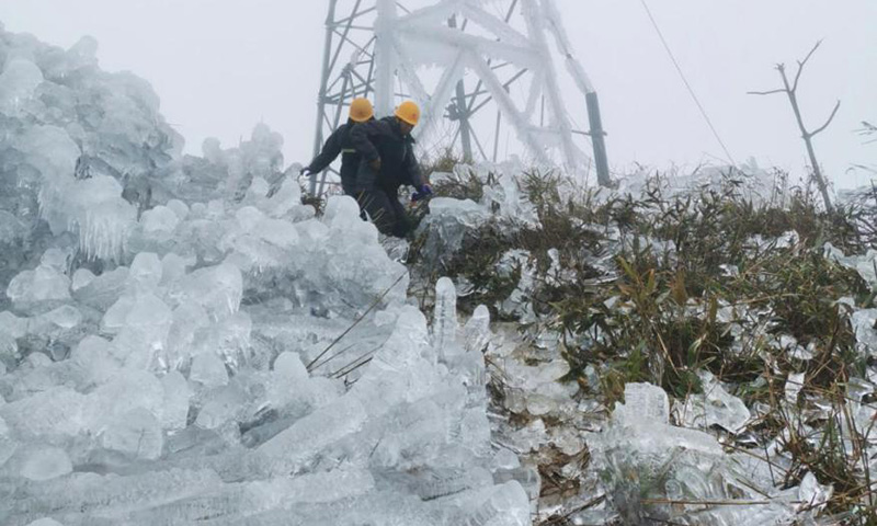 積冰堵塞了本就陡峻的山路，車輛無法通行，突擊隊員徒步穿過晶瑩的“冰山”，行走的黃色安全帽在高高的山頂格外耀眼。