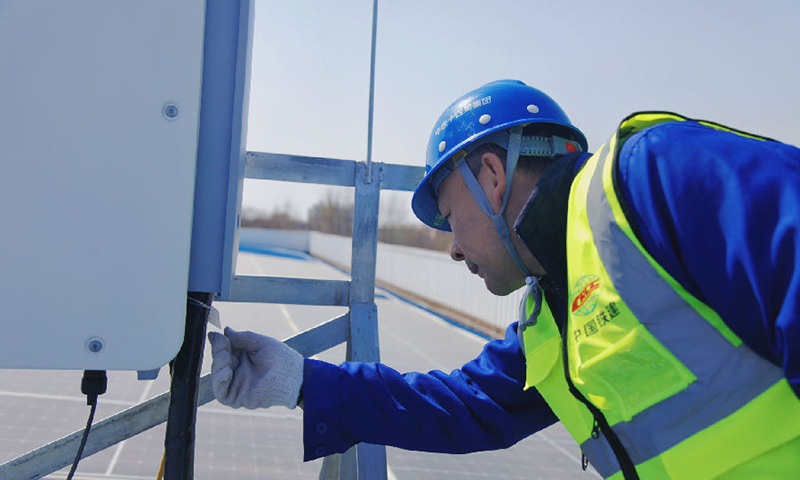 南水北調(diào)北京段房橋光伏發(fā)電項目位于太陽能資源豐富的北京市房山區(qū)，中鐵十四局電氣化公司施工建設(shè)者采取“自發(fā)自用，余電上網(wǎng)”方式進行設(shè)計，并采用全球領(lǐng)先的光伏組件，將太陽能通過光伏組件轉(zhuǎn)換為直流電，再通過逆變器將直流電轉(zhuǎn)換成交流電。圖為技術(shù)人員檢查現(xiàn)場設(shè)備。