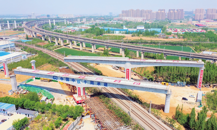 近日，中國中鐵旗下中鐵十局承建的濟（南）鄭（州）鐵路濟南上行聯(lián)絡(luò)線、下行聯(lián)絡(luò)線轉(zhuǎn)體橋同時跨越京滬鐵路和水（屯）白（馬山）鐵路，順利對接，成為濟鄭鐵路首座實現(xiàn)雙橋同轉(zhuǎn)的橋梁工程。該轉(zhuǎn)體橋為雙幅變梁高T型剛構(gòu)橋，轉(zhuǎn)體長度128米，單幅轉(zhuǎn)體重量為6500噸，轉(zhuǎn)體過程中，兩橋?qū)崿F(xiàn)了不同轉(zhuǎn)角、不等速同轉(zhuǎn)。圖為施工現(xiàn)場。 