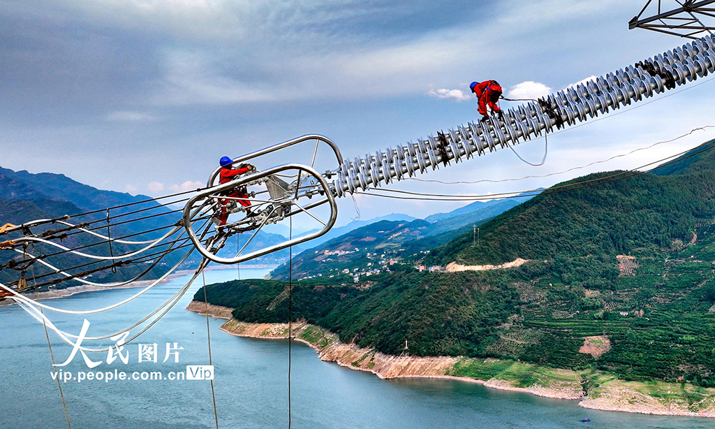 ±800千伏特高壓直流輸電線路工程白浙線，屬我國實(shí)施“西電東送”戰(zhàn)略的重點(diǎn)工程，是促進(jìn)國家能源結(jié)構(gòu)調(diào)整和節(jié)能減排的重大清潔能源項(xiàng)目。白浙線為白鶴灘水電站電力外送二期工程，起于四川省涼山州布拖縣，止于浙江省杭州市余杭區(qū)，線路全長2140.2千米。圖為2022年8月20日，湖北省恩施土家族苗族自治州巴東縣東瀼口鎮(zhèn)綠竹筏村，電力工人冒著40℃以上的高溫跨越長江施工作業(yè)。張遠(yuǎn)明 攝
