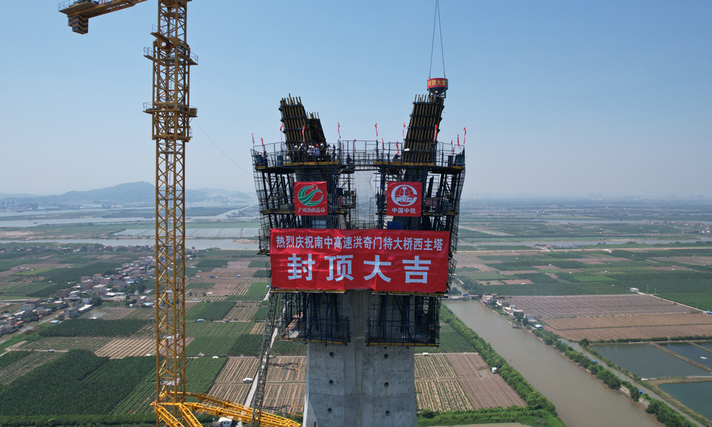 主塔采用全自動液壓爬模系統(tǒng)進(jìn)行施工，在主塔兩肢合龍后逐漸向外傾斜展開，形成“花開”造型，這對液壓爬模軌道在空中進(jìn)行換軌帶來了較大挑戰(zhàn)。項目部將直軌道優(yōu)化為與主塔線型契合的弧形軌道，在縮短每個節(jié)段施工周期的同時，也有效保障了塔柱高空施工作業(yè)安全。圖為洪奇門特大橋西主塔封頂。