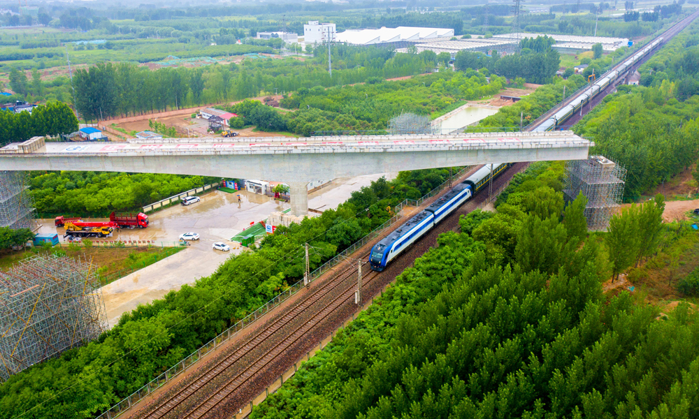 近日，中國中鐵旗下中鐵四局承建的雄安新區至北京大興國際機場快線跨京九鐵路轉體梁順利合龍，為全線按期通車運營奠定了堅實基礎。圖為跨京九鐵路轉體梁轉體后火車經過轉體橋。
