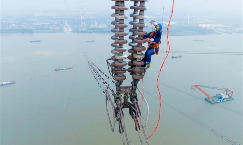 國家電網(wǎng)江蘇南京供電公司工作人員在500千伏汊龍汊王線跨江高塔上使用高壓泵給絕緣子噴涂防污閃涂料，提高其絕緣性能。
