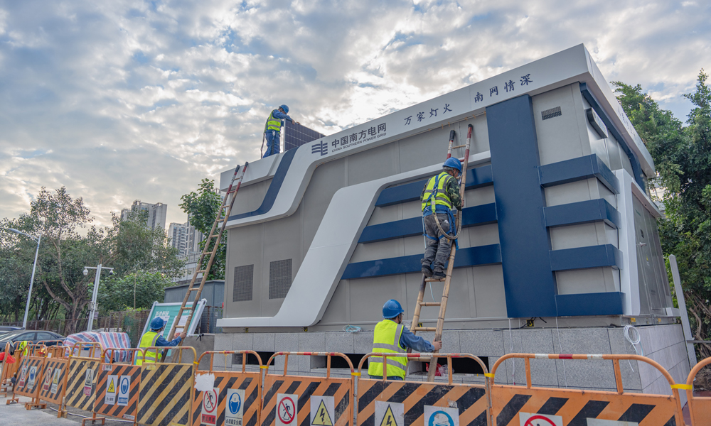 近日，南方電網首座全預裝近零碳景觀配電站在深圳投運。因其外形酷似魔方，也被稱為“電力魔方”。它是將預制艙、標準化設備、零碳裝備、智能傳感器等，在工廠內完成標準化預制生產、集成裝配“一條龍”，最后整站成套交付的產品。現場“搭積木式”拼裝，實現配電站從“建”到“買”的轉型。圖為工作人員在現場進行全預裝近零碳景觀配電站光伏系統安裝。