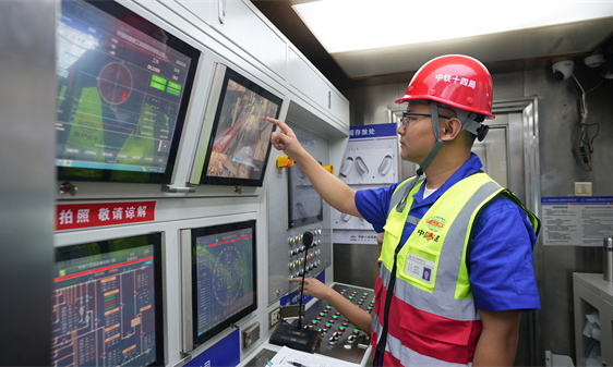 項目建設團隊采用高精度北斗衛星定位技術，進行鐵路路基安全監測，嚴格控制現場施工設備的工作半徑與站位，確保不對既有線路接觸網產生影響。施工期間，項目數字化智慧指揮中心利用測量數據，指導盾構機精準平穩前進，誤差控制在毫米級。圖為技術人員監控盾構機運行情況。