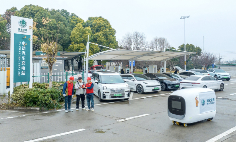 國家電網安徽馬鞍山供電公司工作人員在高速公路充電站指導客戶操作充電機器人。