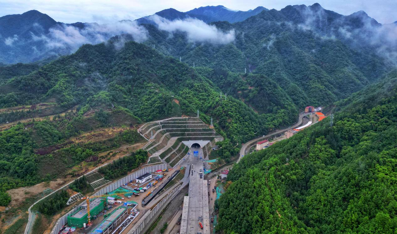 五月的陽光熾烈如火，中國中鐵承建的重點工程施工現場呈現出一派熱火朝天的繁忙景象。其中，多個重難點高鐵隧道項目更是接連傳來佳音，順利實現關鍵節點突破，為我國高鐵建設及隧道掘進技術發展作出新貢獻。圖為中鐵七局承建的西安至安康高鐵秦嶺九天山隧道貫通。秦嶺九天山隧道位于陜西商洛柞水縣與鎮安縣交界處，單洞雙線，全長13.3公里，最大埋深1200米，是全線二級高風險隧道和重點控制性工程。