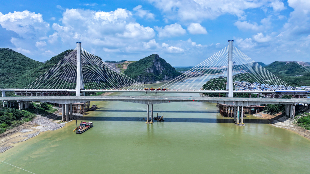 大橋兩個主塔分別高158米、155米，其截面復雜變化與傾斜角度大，對線形控制精度等要求極高。項目團隊引入智能爬升系統，搭配中塔柱主動橫撐系統，實時增強結構剛度以抵抗變形，實現主塔線形誤差控制達毫米級。大橋主梁總重約7200噸，分38段在江面懸臂拼裝。作業區常有大風、航道船只密集，拼裝難度較高。項目團隊在關鍵位置安放智能雷達和攝像頭，并利用AI分析預防碰撞。在鋼箱梁上安裝傳感器，將應力、姿態數據實時傳回“云端大腦”，動態指導施工，最終實現精準合龍。