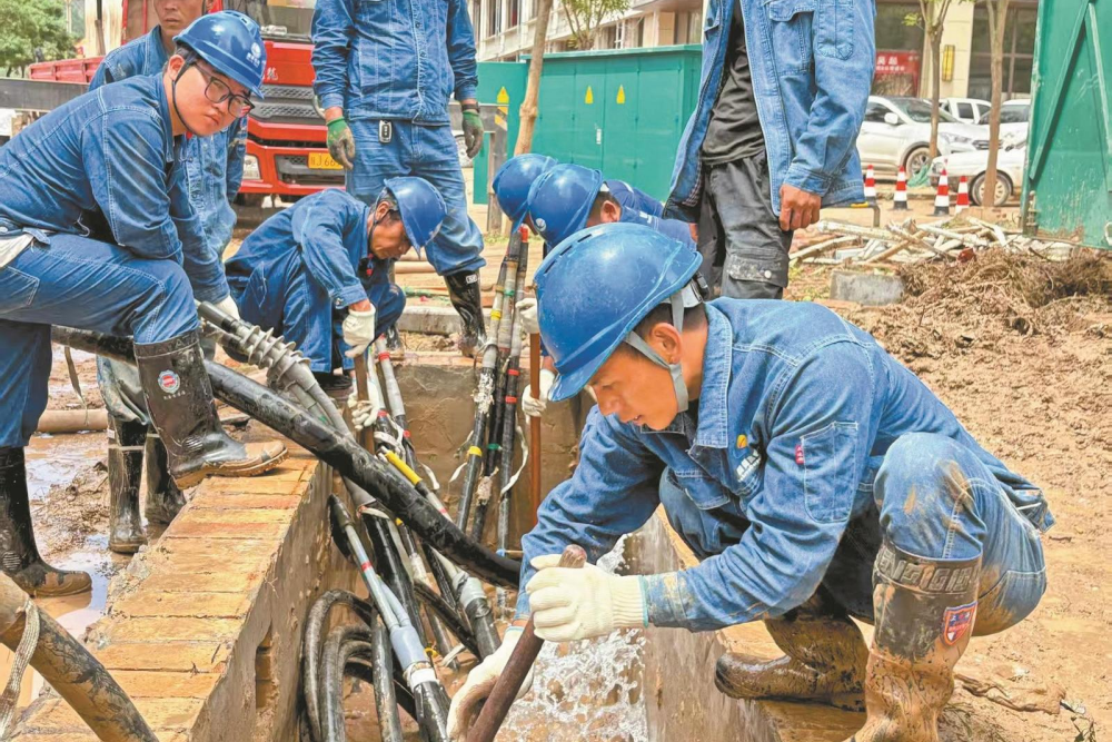 7月26日，陜西延安吳起供電公司搶修員工石磊、李治林等在吳起縣長征街清理10千伏縣城三線12號環網柜電纜溝的淤泥和積水。