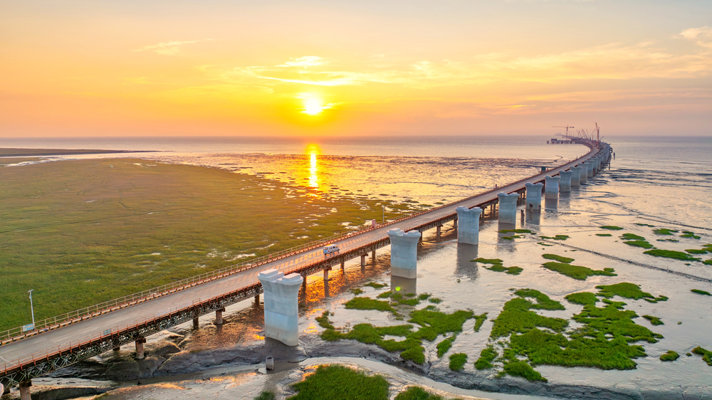 落日熔金，蜿蜒的橋墩如長龍靜臥杭州灣。目前，中交二航局參建的世界最長鐵路跨海橋梁——杭州灣跨海鐵路大橋樁基基礎施工已完成，正全面轉入塔柱施工、箱梁架設等上部結構施工階段。