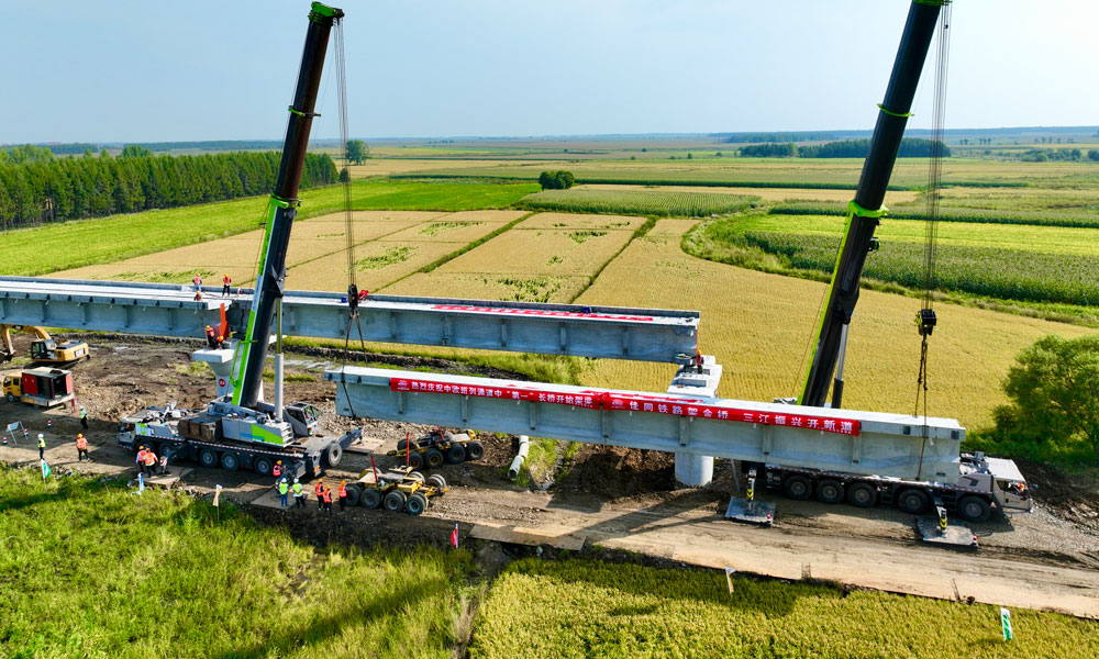 此次進入架梁階段的佳木同江特大橋位于同江至同江北改建段，是全線控制性工程，橋梁全長10435.14米，采用單線T梁結構設計，是我國目前中歐班列三大通道中口岸段最長新建橋梁。圖為架橋機在架設梁體。