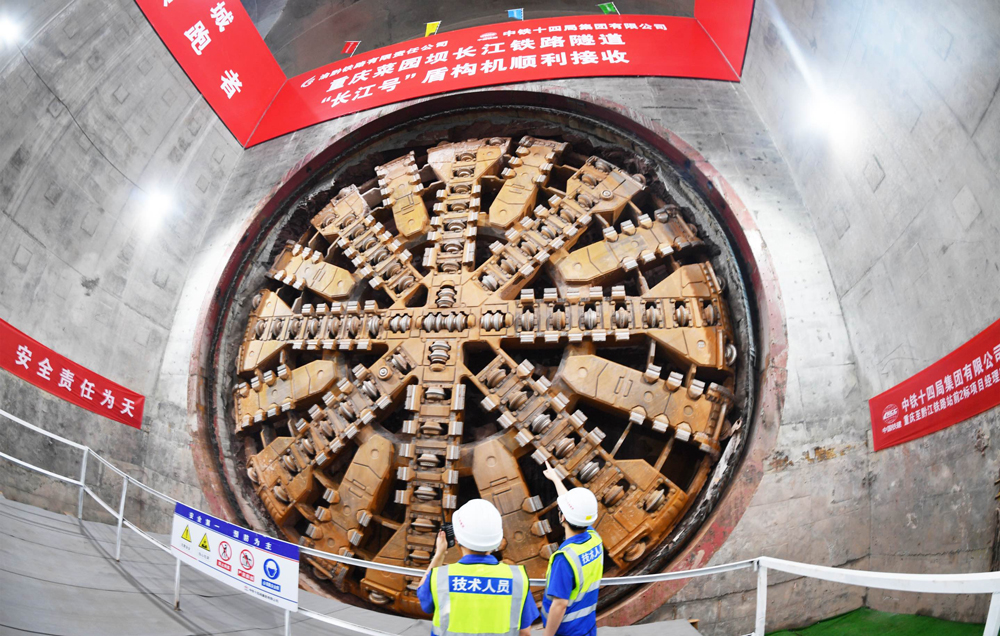 重慶菜園壩長江鐵路隧道是渝廈高鐵全線關鍵控制性工程。隧道位于重慶市渝中區與南岸區，為單洞雙線高速鐵路隧道，全長11942米，起始于重慶火車站，沿途下穿市政道路、高架橋梁、軌道交通線、多處建筑群、長江主航道及南山山體，整體呈現“穿山、穿城、穿江、穿水”的復雜特點，施工難度大、技術要求極高。圖為技術人員檢查刀盤磨損情況。