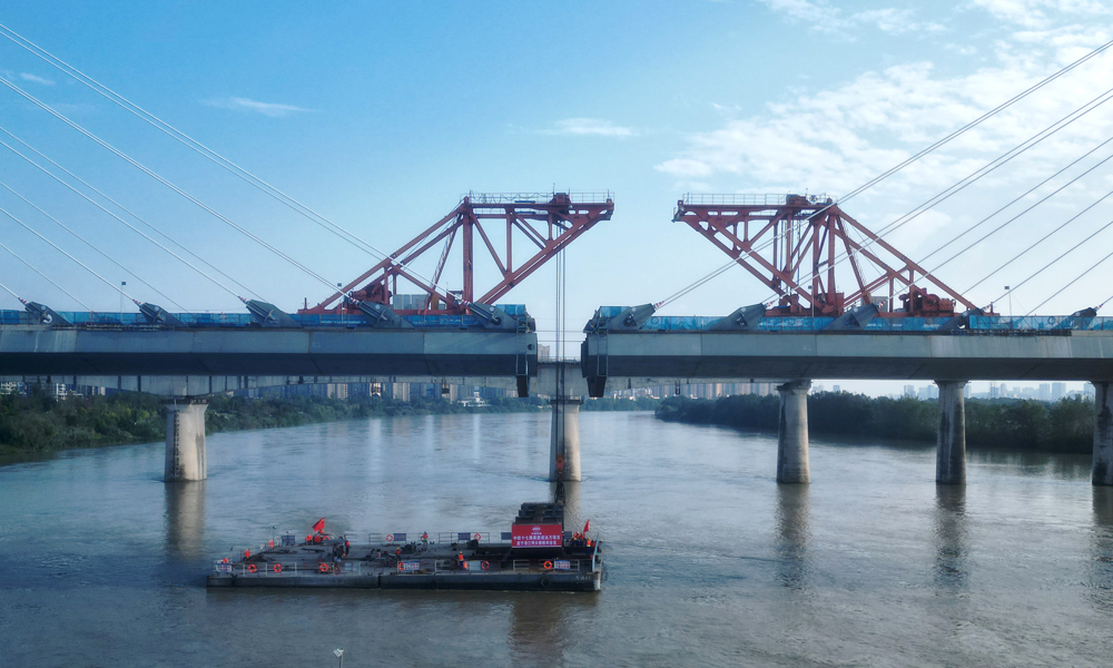 遂寧涪江特大橋是全線“3隧4橋”重難點(diǎn)控制性工程之一，大橋全長(zhǎng)5585.4米。主橋?yàn)椤癏”型特殊結(jié)構(gòu)雙塔雙索面鋼混結(jié)合梁斜拉橋，主跨長(zhǎng)305米，在雙塔雙索面鋼混結(jié)合梁斜拉橋中主跨長(zhǎng)度位居西南第一，全國(guó)第二。圖為大橋鋼箱梁吊裝作業(yè)現(xiàn)場(chǎng)。