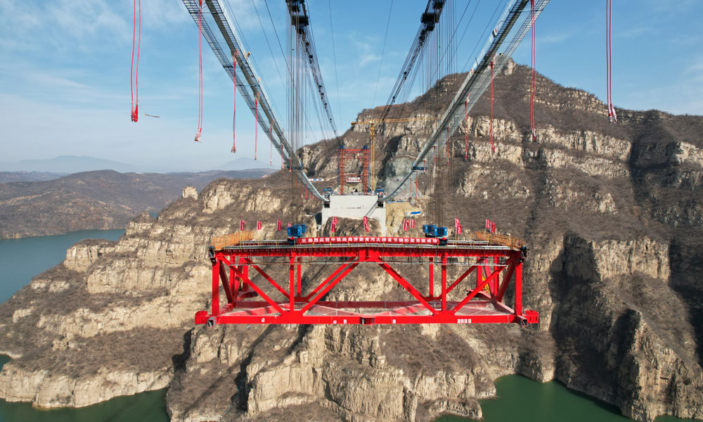 2月14日，中鐵四局承建的濟新高速公路黃河大橋首節鋼桁梁吊裝，標志著世界最大跨度回轉纜懸索橋正式進入橋面安裝階段，為實現2025年底全線建成通車目標奠定堅實基礎。濟新黃河大橋位于河南省濟源市與新安縣交界的王屋山-黛眉山世界地質公園內，橫跨黃河小浪底庫區，主跨555米，塔高109米，采用雙向六車道高速公路標準建造。本次吊裝的首節鋼桁梁長17.9米，桁高7.5米，橋面寬37.4米，重約260噸。全橋由34節鋼桁梁組成，總重約10200噸。