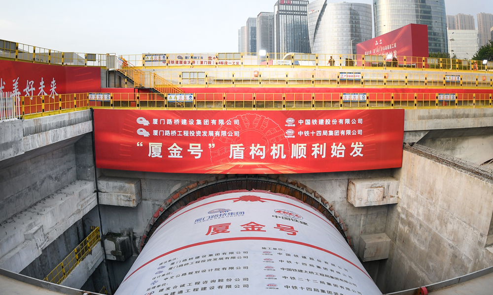 廈金大橋（廈門段）工程起于廈門環島東路與會展北路交叉口，以隧道形式沿環島路向北延伸至觀音山，往東以橋梁形式跨越本島東部海域，終點設互通接入廈門翔安國際機場，主線長17.34公里。其中，環島路隧道長3.29公里，采用盾構、明挖法施工，盾構隧道左右線分別為1.33公里與1.04公里，為雙向六車道，設計時速80公里，由一臺16米級超大直徑盾構機掘進。圖為“廈金號”盾構機始發現場。