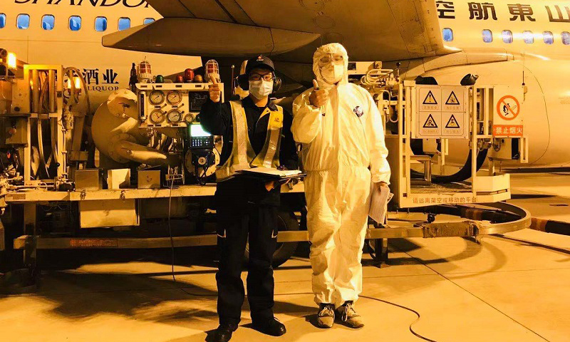2月9日20時，武漢航空加油站飛機加油員正在保障馳援武漢的山東航空飛機供油。工作完成后，機組人員豎起大拇指，與飛機加油員合影，為武漢加油。（李菁 攝）
