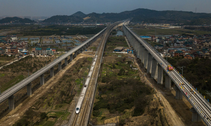 3月12日，中鐵四局施工技術人員在傳芳特大橋上進行杭黃鐵路的鋪軌作業，一列高鐵從旁邊的滬昆客運專線上駛過（無人機拍攝）。（新華社記者 黃宗治 攝）